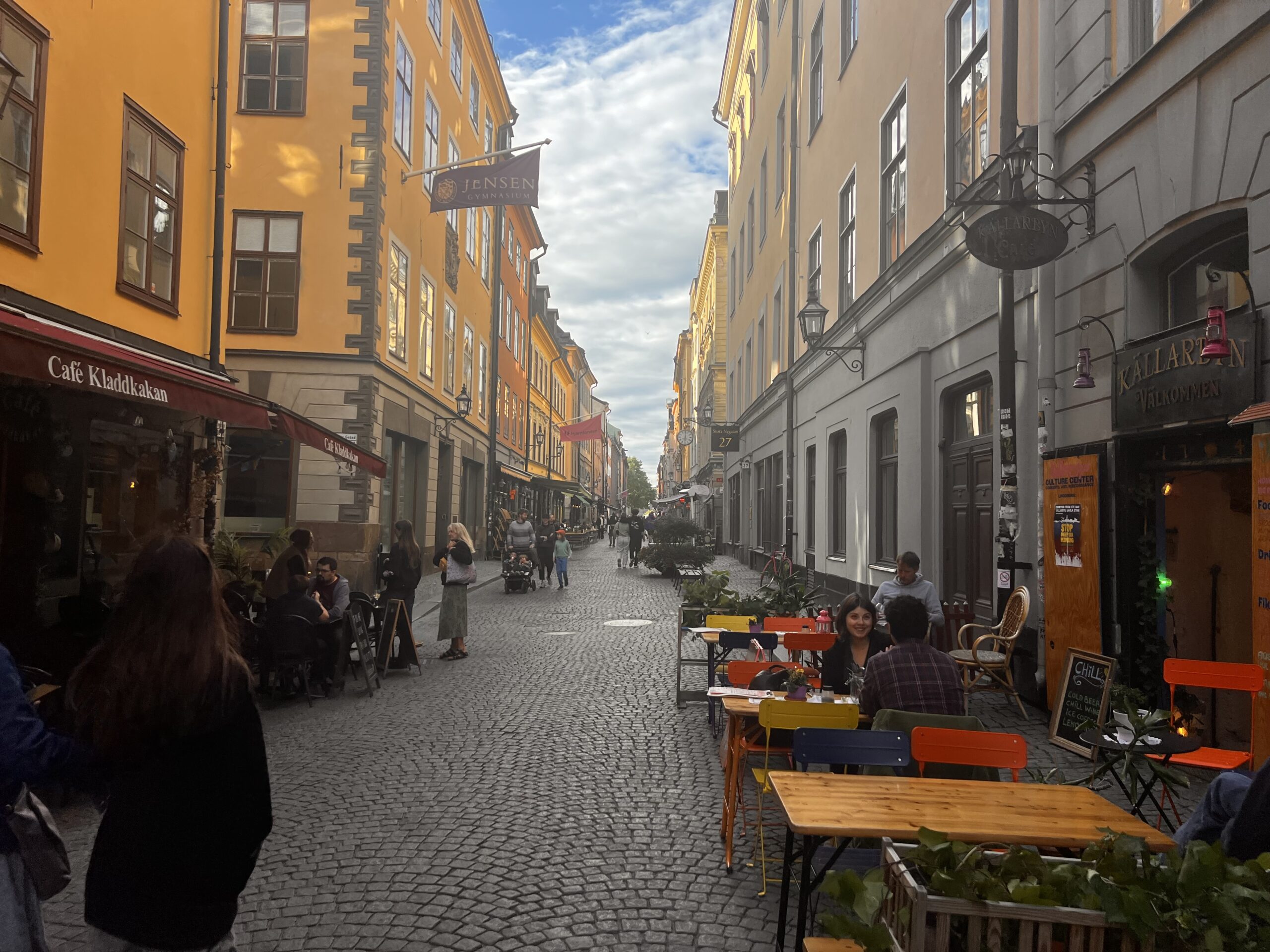 ガムラスタン旧市街のカフェ通り、黄色い建物と石畳、テラス席で寛ぐ人々